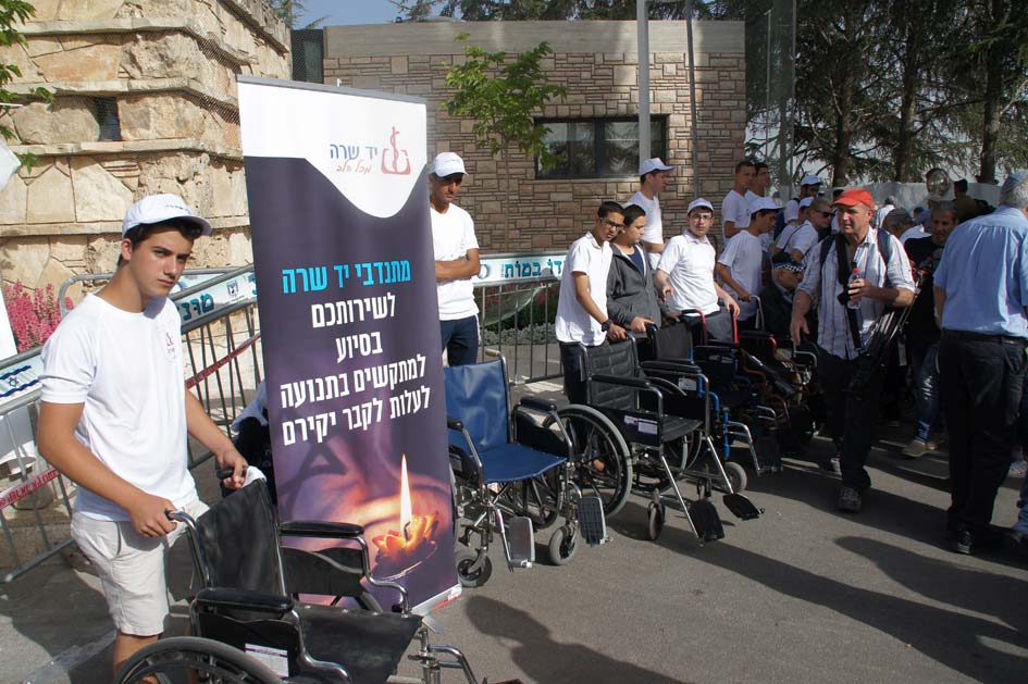 Yad Sarah volunteers stand behind wheelchairs prepared to assist physically disabled reach the gravesites of their lost ones on Memorial Day 2018.