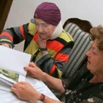 Two women looking at the booklet from the Life Story Project